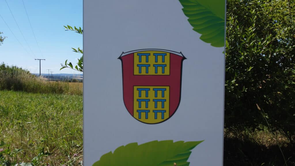 Das Gemeindewappen an einer E-Ladesäule am Park & Ride Parkplatz gegenüber der Hühnerkirche